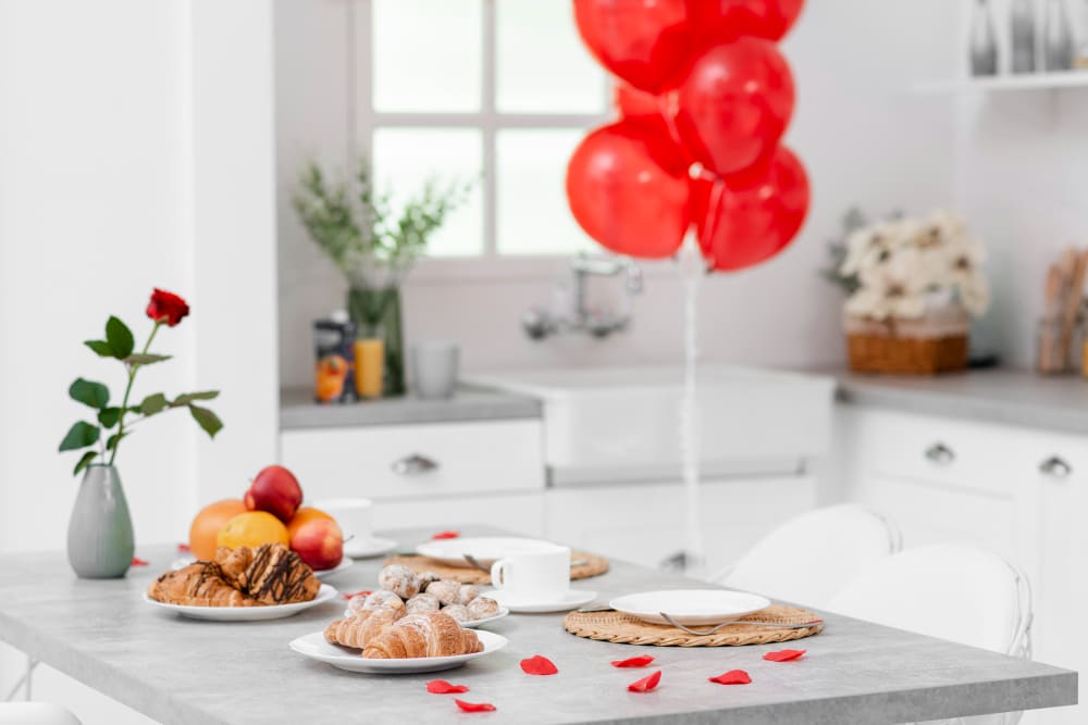 A calm kitchen table set with breakfast, fresh fruit, and flowers